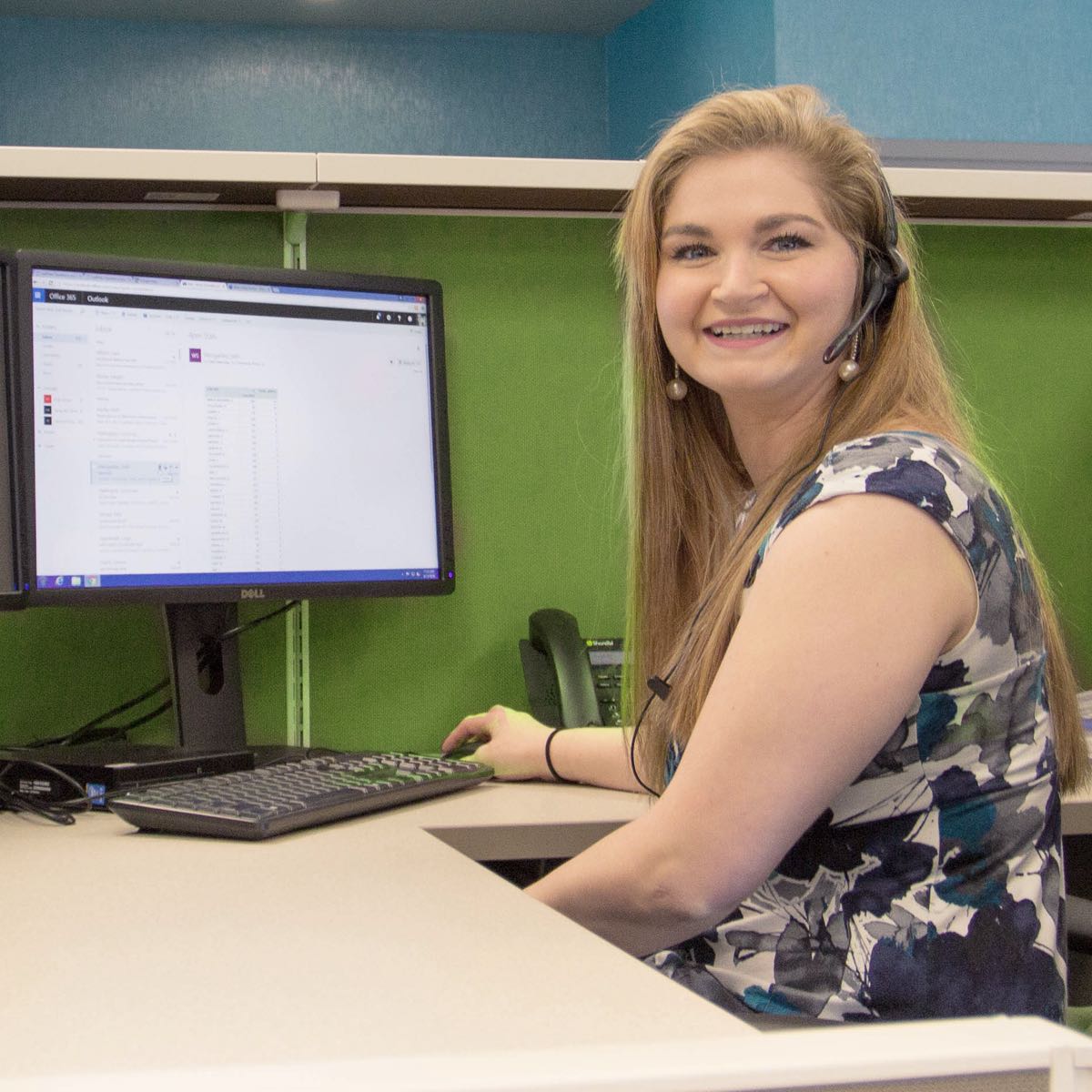 Smiling call center representative sitting near computer