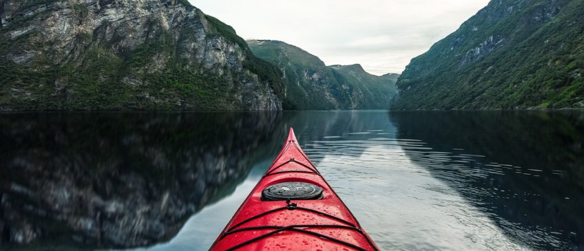 Kayak on open water with mountains in the background