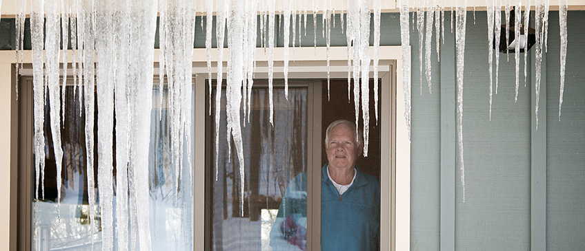 A homeowner looks at icicles with frustration